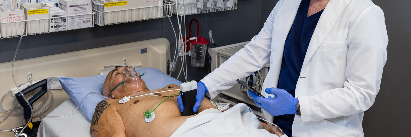 A man in a lab coat tests a portable ultrasound device on a patient