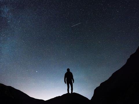 A silhouetted figure stands in front of a night sky background